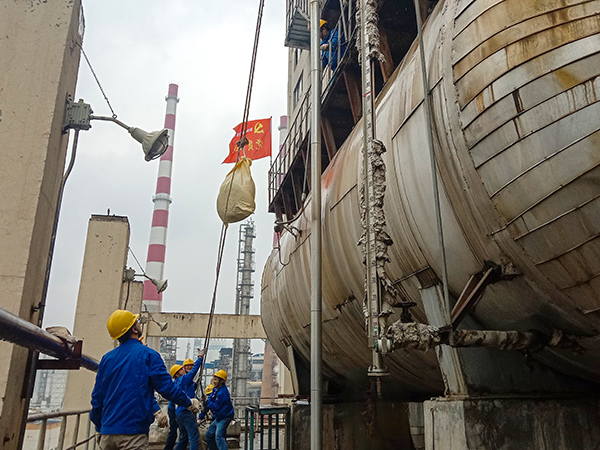 5月10日中午，在動力車間三期工藝除氧器地面，黨員突擊隊隊員用滑輪往工藝除氧器平臺運送鋼絲網(wǎng)，用以纏繞新填料.jpg